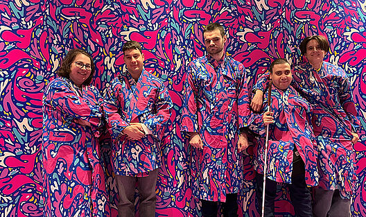 In ihren lila-rosa-blau-weiß gemusterten Mänteln scheint die Jugendgruppe beinahe mit der identisch gestalteten Rückwand zu verschmelzen, eine eindrucksvolle Kunstinstallation des Ikono-Erlebnismuseums.