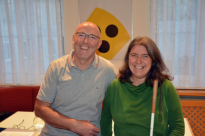 In den Braille Stuben lehnen Karl Mayr und Marion Putzer-Schimack bequem an der Kante des Moderationstisches und lachen herzlich in die Kamera