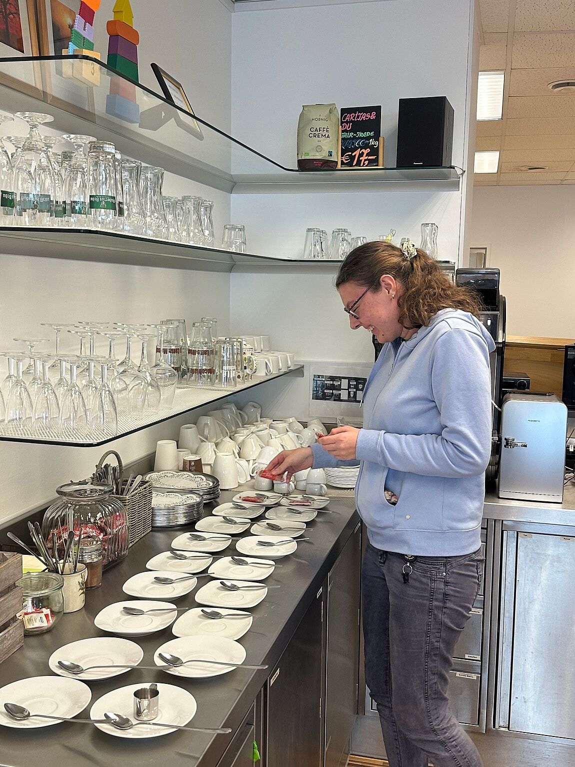 Eine junge Frau bestückt Unterteller mit kleinen Löffeln und Süßungsmitteln.