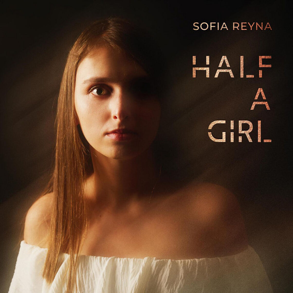 Das Gesicht einer jungen Frau mit glatten langen Haaren, nur rechtsseitig beleuchtet, die linke Gesichtshälfte ist im Dunklen. Text: Sofia Reyna HALF A GIRL