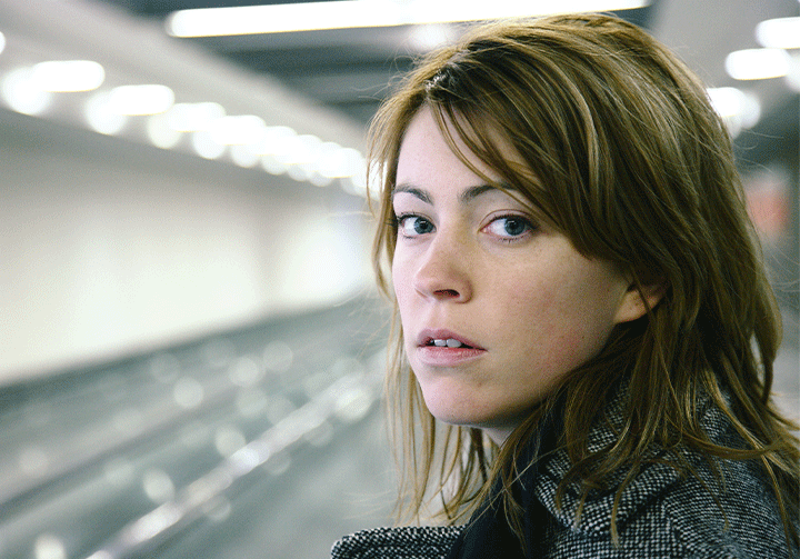 Eine junge Frau, die an einem Bahnsteig wartet. Sie sieht unsicher aus.