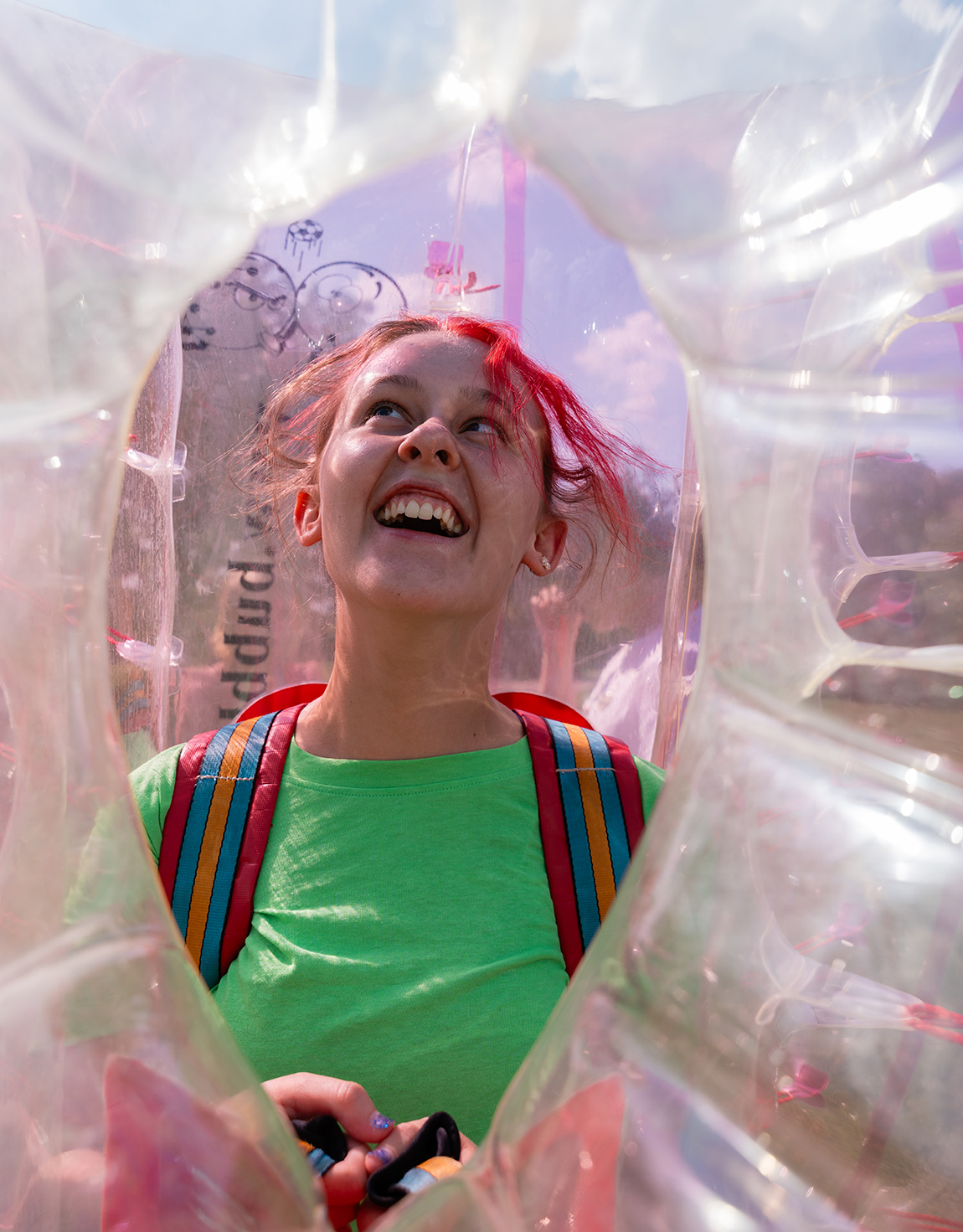 Eine lachende Jugendliche mit dem umgeschnallten Riesenball, fotografiert durch eine der Öffnungen.
