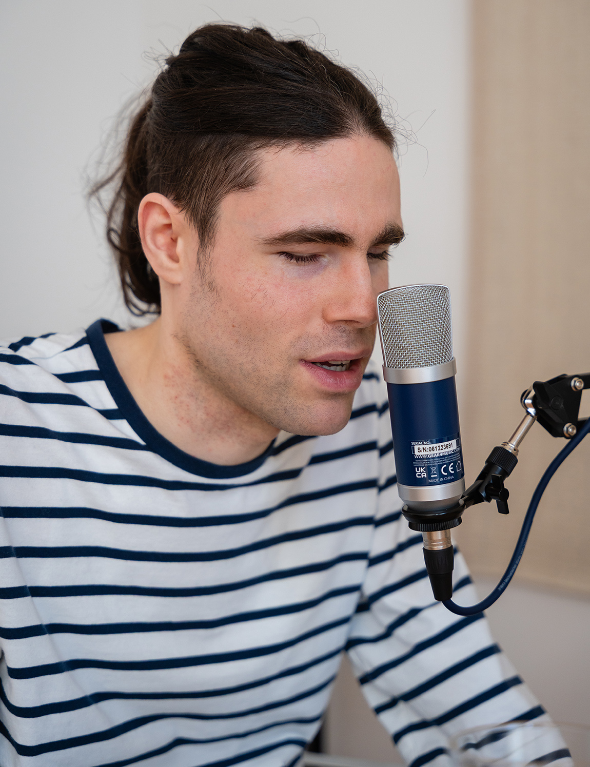 Mit dem Mund und der Nase dicht vor dem Mikrofon, das die Form eines großen Deosprays hat.