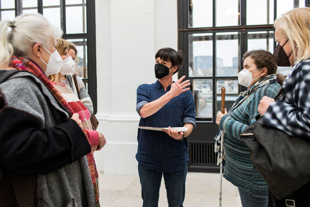Sechs Frauen stehen, alle mit Mundschutz, in einem Raum des Belvedere beisammen.