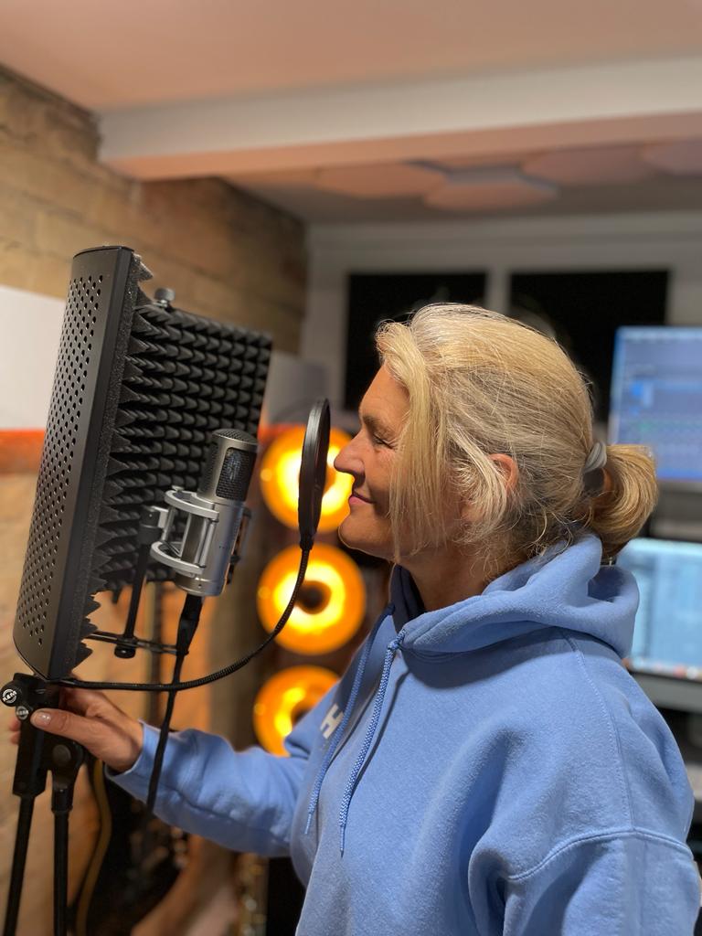 Im Studio mit zusammengebundenen Haaren: Ute Ullrich vor einem professionellen Studiomikrofon.
