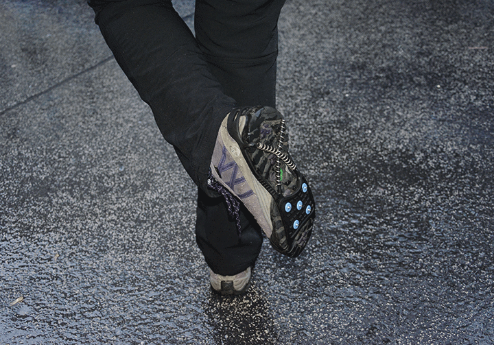 Nahaufnahme von den Beinen einer Person, die Spikes an ihren Turnschuhen trägt.